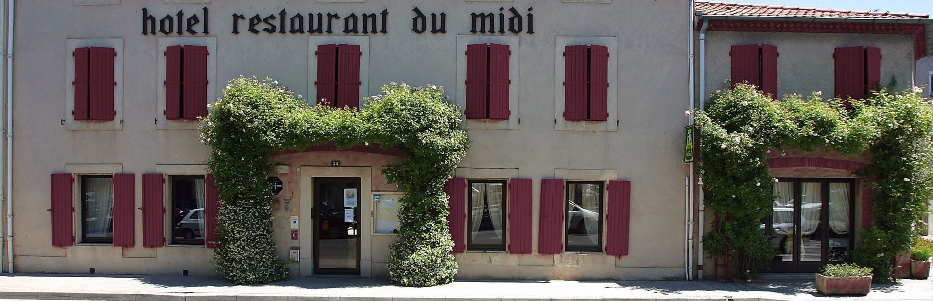 Façade de l'Hôtel Restaurant du Midi à Revel, entrée fleurie de rosiers grimpants